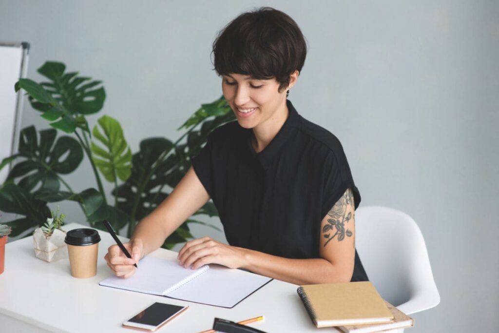A remote nonprofit worker working at home, writing in a notebook.