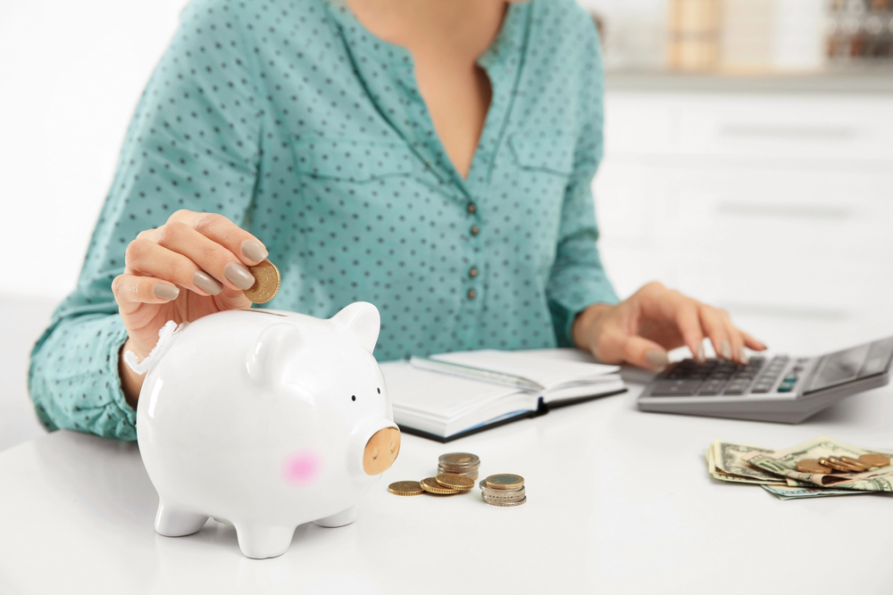 A woman putting money into a piggy bank for blog post things to rent for money