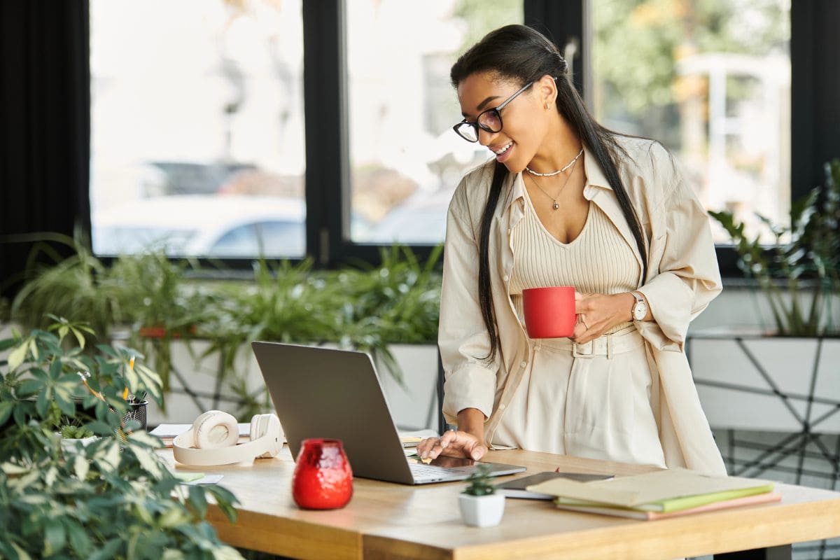 A woman reviewing her career goals on her laptop while drinking coffee.