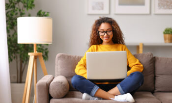 Young female sitting on the sofa looking at her laptop looking for work from home jobs for teens